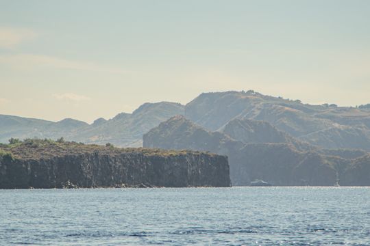 Layered volcanic hills beyond the rocky shore